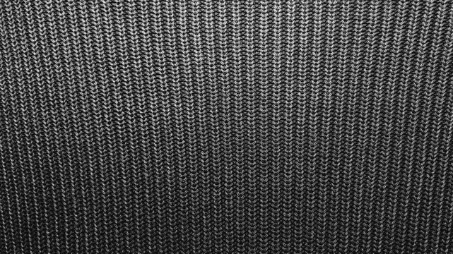 macro tracking shot reveals complex texture of dark gray knitted wool fabric shifting under dramatic cinematic lighting