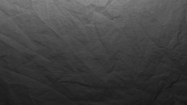 cinematic tracking shot glides over textured black crumpled linen fabric shifting under moody chiaroscuro lighting