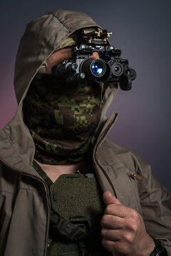 Vertical portrait of low profile operator in civilian jacket over body armor wearing night vision monocular and thermal imager fusion setup