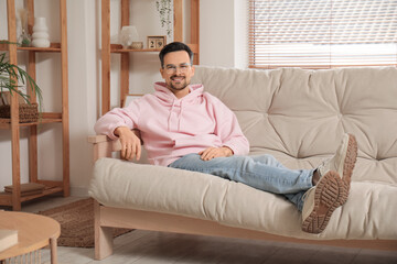 Obraz premium Handsome young man in eyeglasses lying on sofa at home