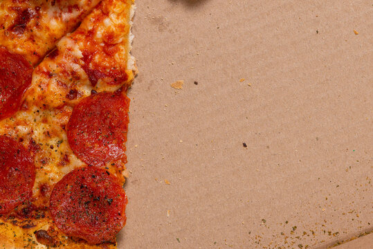 Detailed top down macro view of pepperoni pizza slices inside a cardboard delivery box.