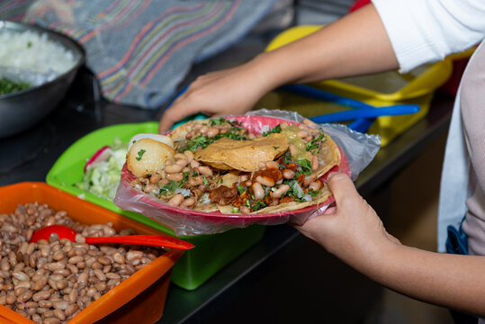 Close-up of hands preparing fresh street tacos with meat, onion and cilantro
