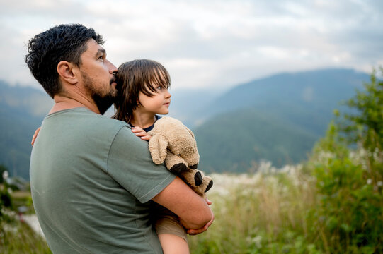 Father carrying son with teddy bear at vacation