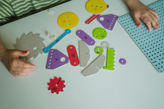 Hands playing with colorful mechanical toy gears on a table
