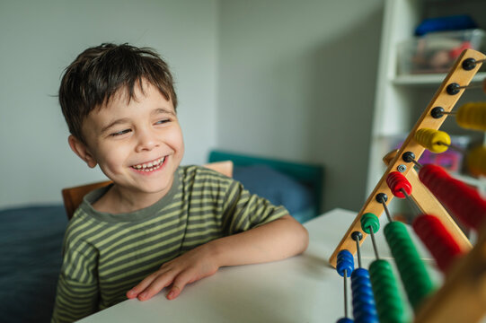 Happy student learning mathematics with a wooden abacus indoors