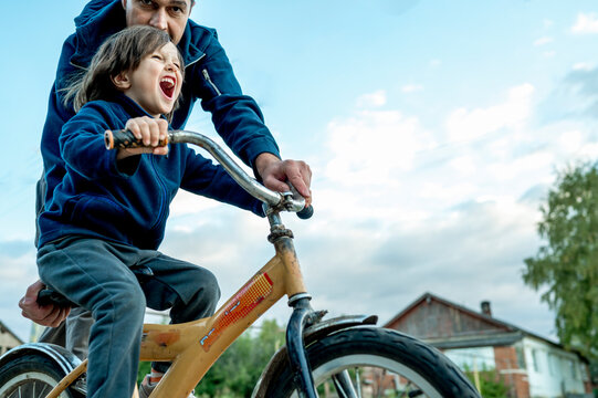 Cheerful boy riding bicycle by father