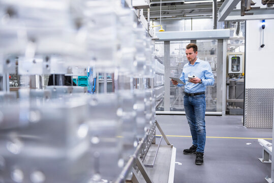 Man with tablet in factory shop floor examining products