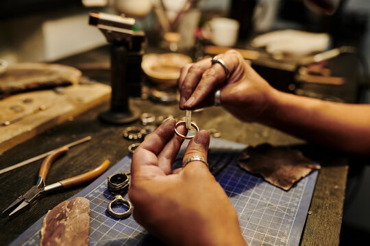 Hands of craftswoman repairing ring at workbench