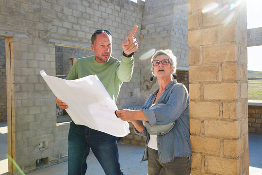 Architect and homeowner discussing building plans on construction site
