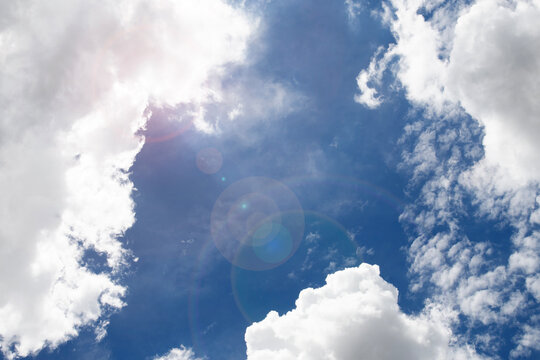 Sunlight shines through the white clouds in the bright blue sky.