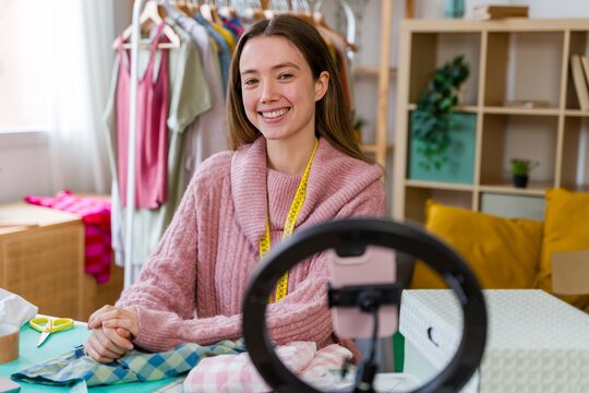 Smiling fashion designer streaming video indoors at workspace