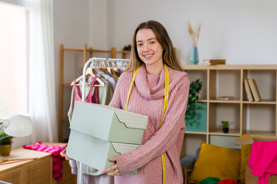 Smiling fashion designer holding box in indoor studio