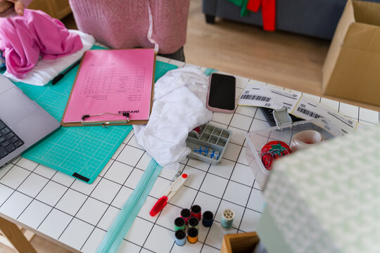 Entrepreneur organizing orders on desk with invoice and fabric