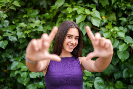 Smiling girl making framing gesture with hands outdoors in garden