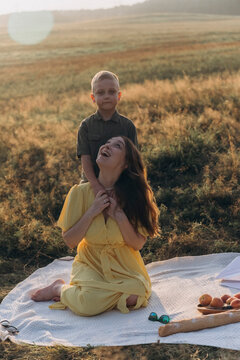 Mother and son laugh during a sunset picnic outdoors