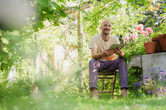 Person working with tablet outdoors in sunny summer garden