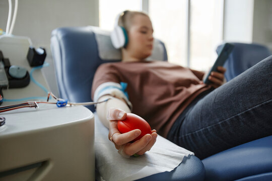 Hand of woman holding soft ball lying on couch at blood donation center