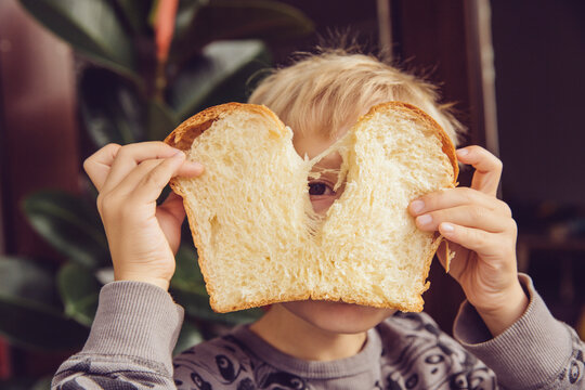 Little boy peeking through slice of white bread