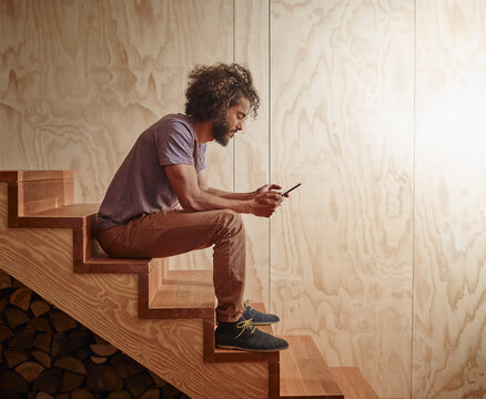Young man sitting on wooden stairs looking at digital tablet