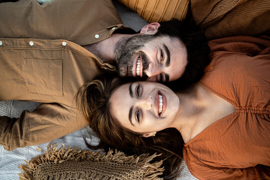 Cheerful girlfriend lying with boyfriend on picnic blanket