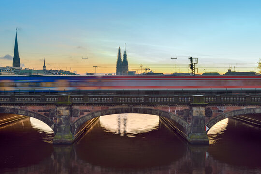 Germany, Hamburg, train on Lombard bridge on the Inner Alster Lake at sunset
