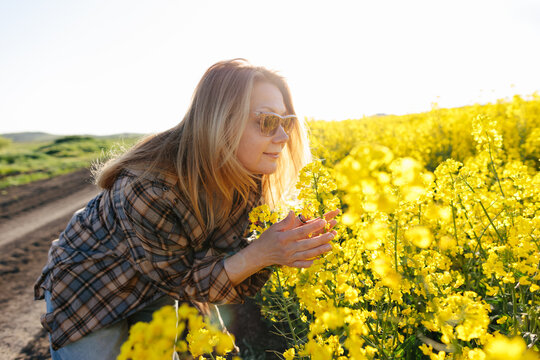 Woman enjoying a mindful moment among yellow rapeseed flowers in nature