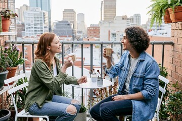 Fototapeta premium Two friends chatting over coffee on rooftop style balcony