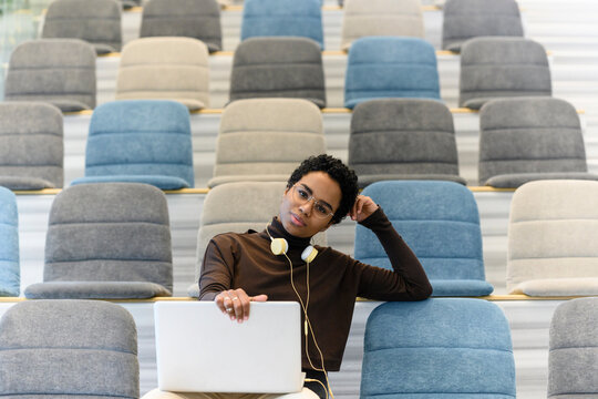 Curly haired woman using laptop at auditorium