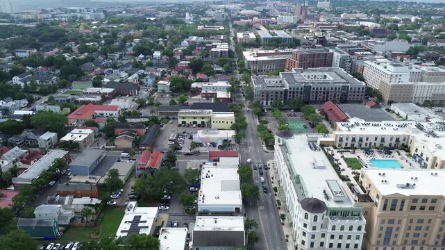 Pool courtyard view near Meeting St Lee St shows mixed use residential blocks north of downtown Charleston. White rooftops, patterned facades, bright pool surfaces contrast with dense foliage, SC