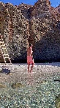 a man wanders along the stunning shoreline of Tsigrado BeachMilos Island, where crystal-clear waters meet breathtaking cliffs. This enchanting landscape captures the essence of a perfect Greek holiday