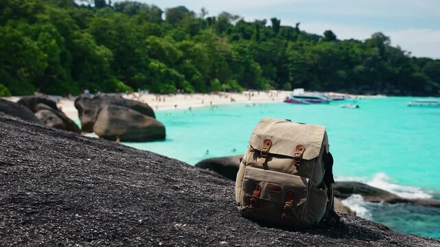 Backpack sitting on rocky outcrop by Turquoise bay beach and rocky islands from cliffside Island Similan in Phang Nga, Phuket Thailand.