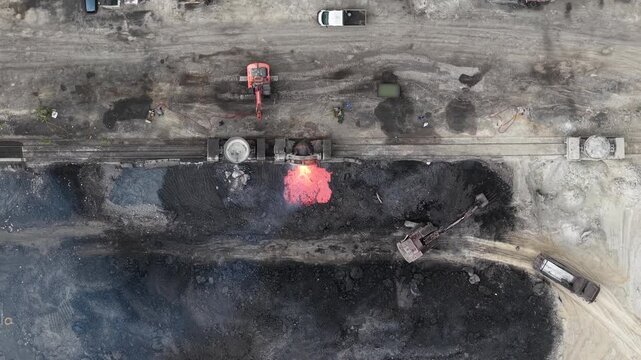 An aerial top-down view shows molten metal slag being poured from a ladle at a large steel factory in Hungary.