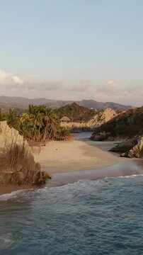 Vertical View Of Rocky Tropical Beach At Playa Maruata On The Pacific Coast Of Michoac&aacute;n, Mexico. Aerial Pullback Shot