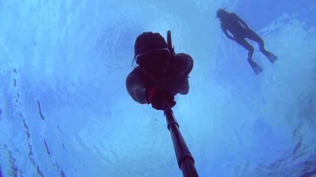 selfie of an young female woman asian free diver wearing bikini snorkel mask holding gopro camera swim descent down into water swimming along at the bottom around coral reef then ascent up to surface 