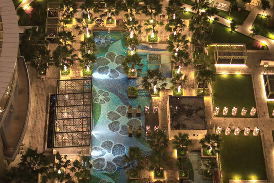 Aerial Nighttime View Shows A Luxurious Apartment Courtyard Featuring An Illuminated Swimming Pool