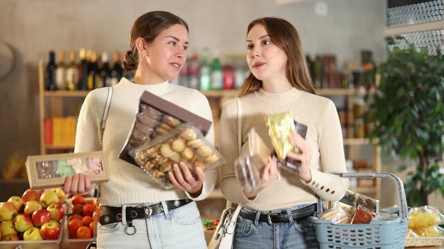 Two friends buy various sweets together - cookies and nougat in a grocery supermarket. High quality 4k footage