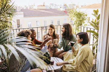 Obraz premium Diverse group of friends sharing coffee on sunny balcony