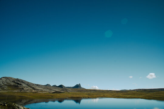 A serene lake reflects the mountains under a clear blue sky in the Peruvian Andes.