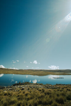 Part of a serene lake that reflects a clear blue sky in the Peruvian Andes.