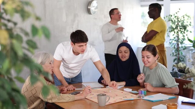 Group of positive of different years people playing tabletop game