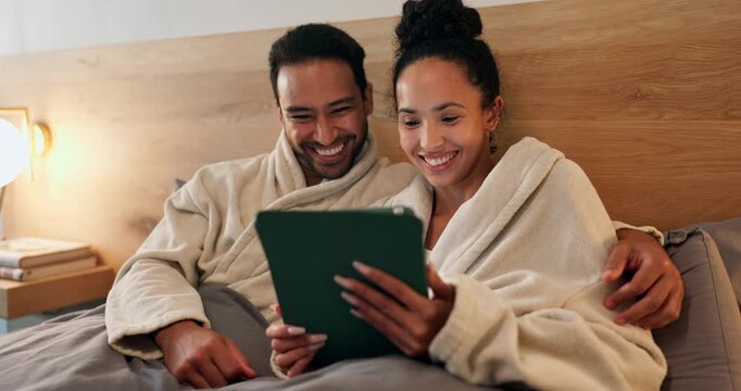 Couple, laugh and relax in hotel room with tablet, social media meme and romantic vacation at night. Late, happy married people and rest in accommodation bed with tech, joke and bonding on holiday.