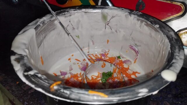 Closeup view of dosa batter with chopped carrots and onions in bowl