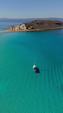 Sail over the stunning turquoise waters of Simos Beach, nestled on Elafonisos Island in Greece. Witness this tranquil paradise, perfect for relaxation and adventure under the golden sun.
