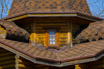 Asphalt shingle roofing detail on rustic log cabin turret © Mariia