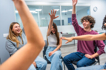 Diverse students raising hands in modern classroom learning and participating © unai