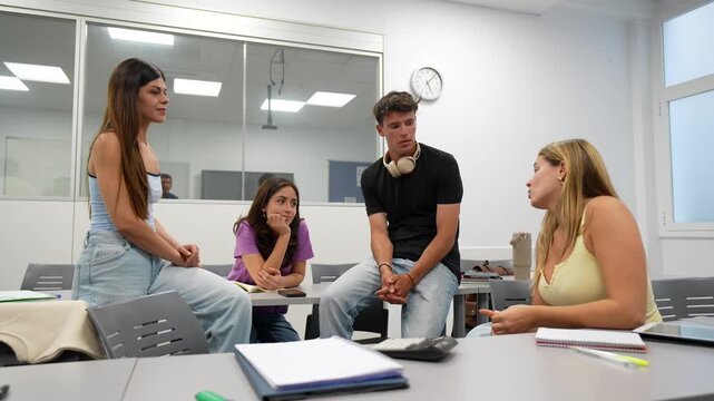 Four young university students engaging in a collaborative discussion around a table in a bright classroom, actively sharing ideas and working together on their academic assignment