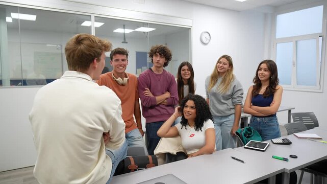 Diverse group of young college students listening attentively to their male classmate during a collaborative session, fostering communication and teamwork in a modern classroom environment