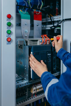 Electrician builder engineer testing and screwing equipment in fuse box and repairing of modern electricity power station using voltmeter. Automatic control cabinet
