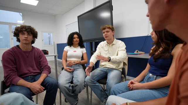 Group of diverse young students sitting in a circle and participating in a supportive therapy session, actively listening and sharing their experiences with a counselor or psychologist