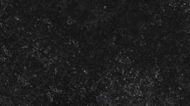 Dark textured surface with subtle circular marks, scattered specks, and faint vertical patterns. Grunge texture background animation.